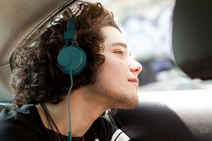 Young man listening to headphones whilst looking out of taxicab window, Rio De Janeiro, Brazil